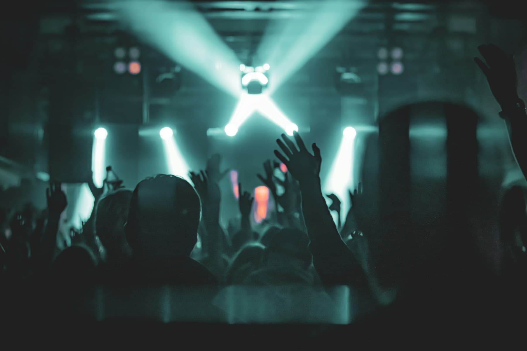 A crowd with hands raised under stage lights