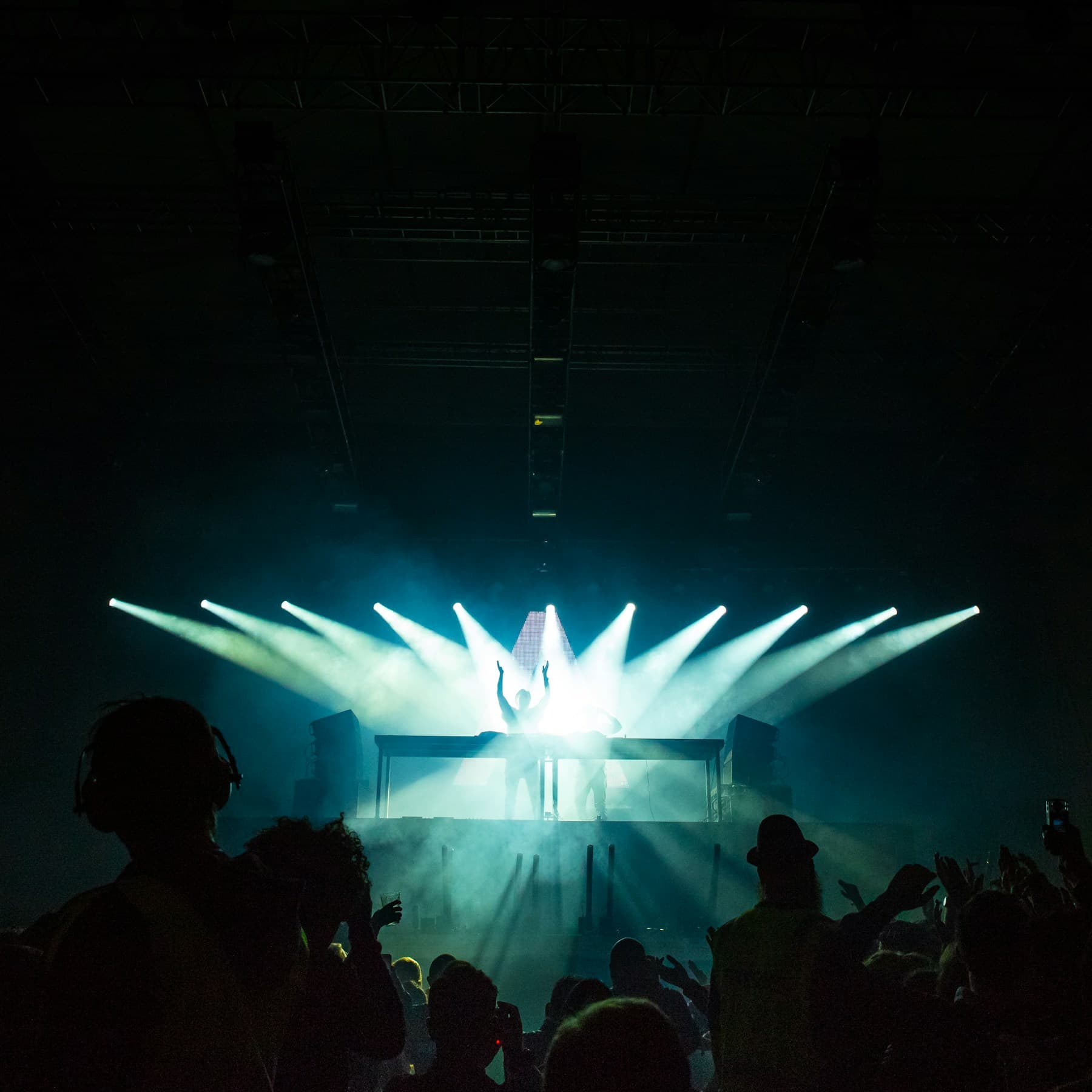 A figure standing under stage lights facing the crowd